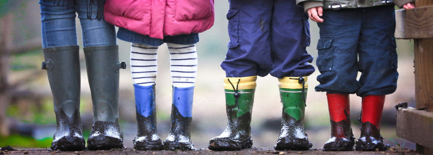 Kids standing in a row with muddy rain boots on