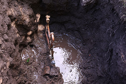 Pipes coming out of the ground with a mud puddle near